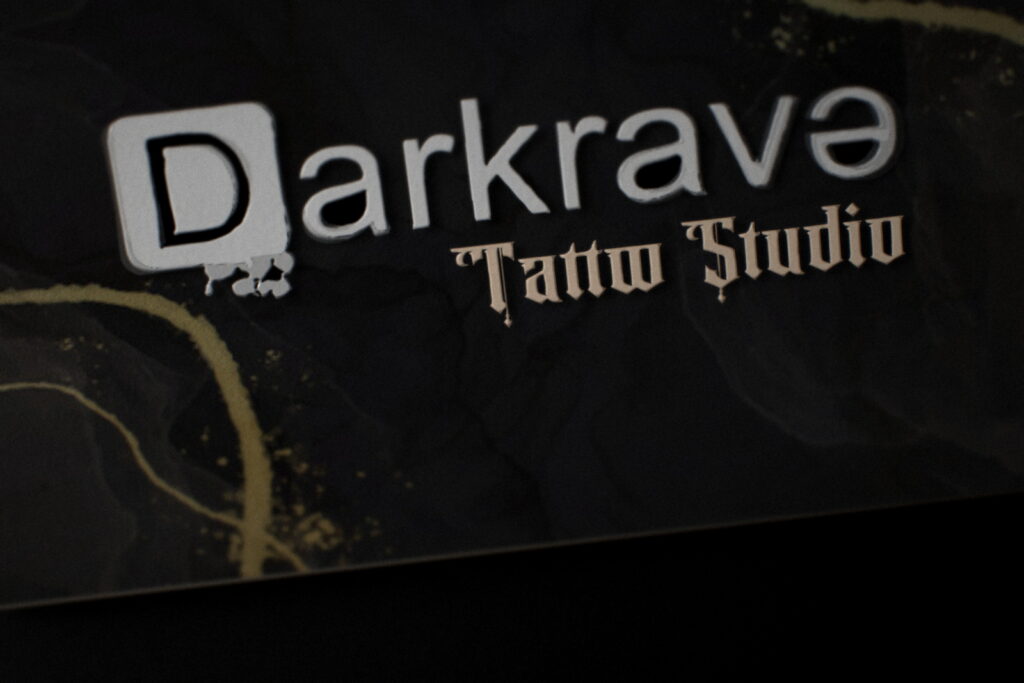 Carte de visite Darkrave Tattoo Studio en gros plan : logo rehaussé d'un vernis 3D brillant sur papier noir soft touch 350 g/m²