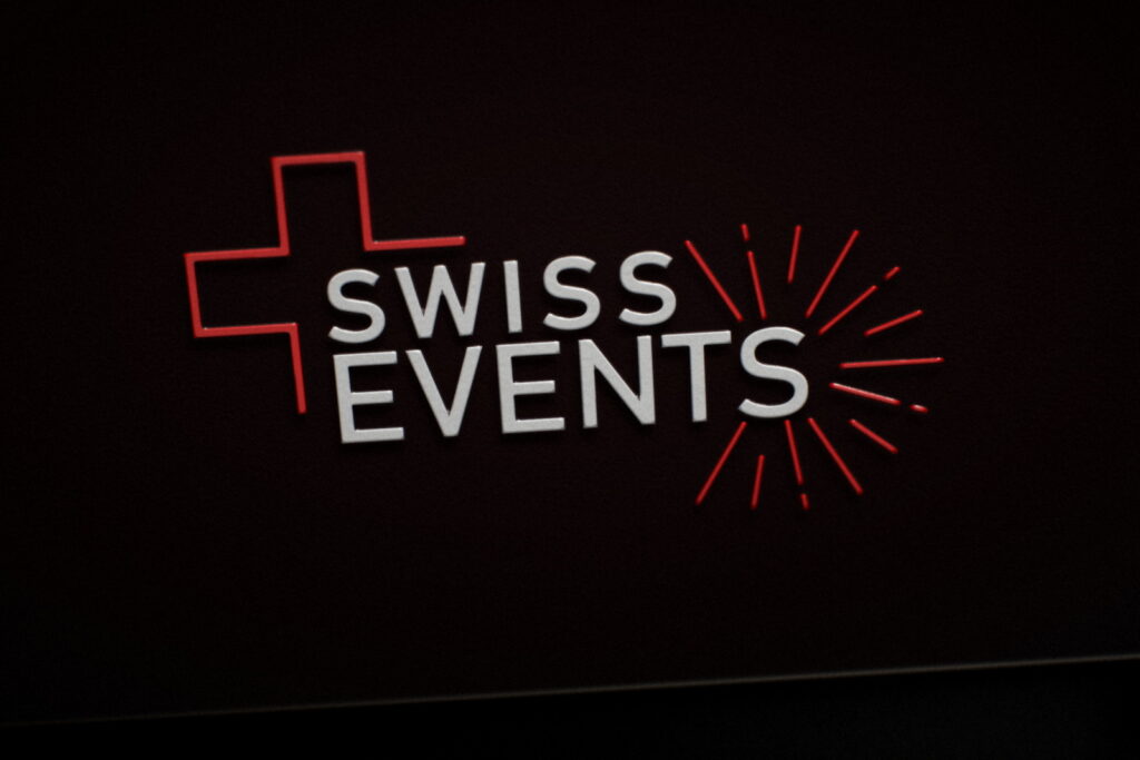 Carte de visite Swiss-Events en gros plan : logo en vernis 3D brillant sur papier noir soft touch